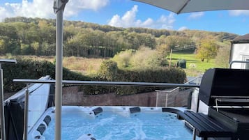 A hot tub with a view of a forested hillside.