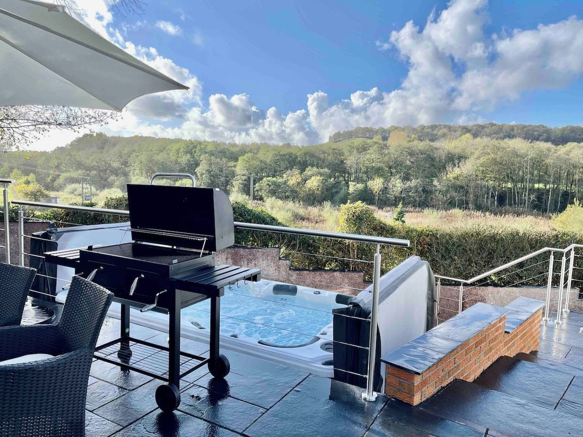 Un patio exterior con un jacuzzi, una parrilla y mobiliario de mimbre.