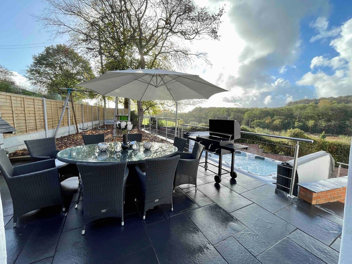 An outdoor patio with a round table and chairs, a barbecue grill, and a swimming pool.