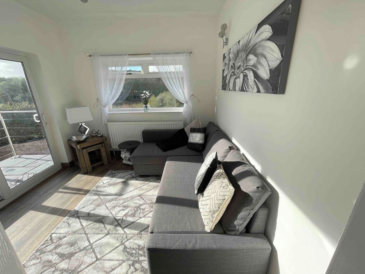 A living room with a sofa, a table, a lamp, and a window with curtains.