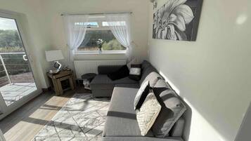 A living room with a sofa, a table, a lamp, and a window with curtains.