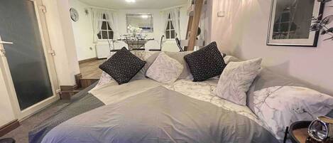 Un dormitorio con una cama grande, una mesita de noche, un espejo y vista al comedor.
