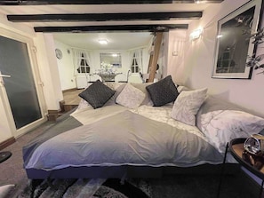 Une chambre avec un grand lit, une table de chevet, un miroir et une vue sur la salle à manger.