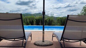 Zwei Liegestühle vor einem Pool mit Blick auf eine Berglandschaft.
