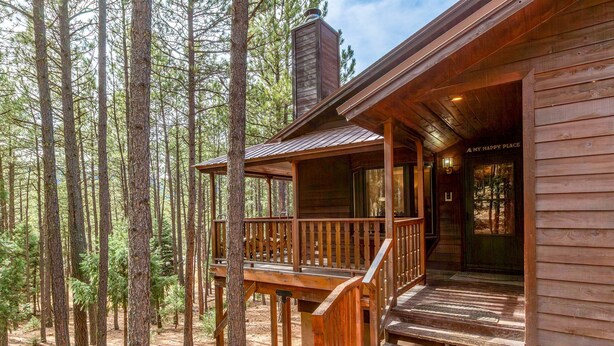 A wooden cabin with a porch, surrounded by tall pine trees. - Cabin Walkable to Lake with Hot Tub, Deck & Views, Pool Table, Near Golf & Bike (Angel Fire)