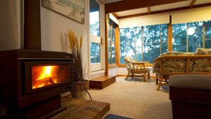 A cozy room with a fireplace, wicker furniture, and large windows. - Seascapes at Rosedale (ROSEDALE)