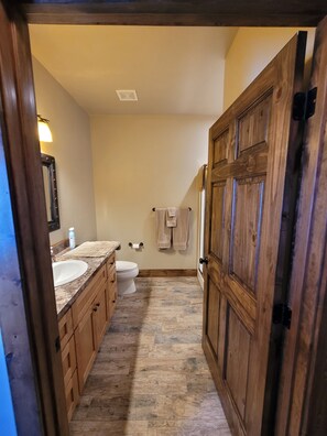 A narrow bathroom with a wooden door, a marble sink, and a toilet. - Star Valley Lodge (Bedford)