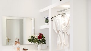 Et moderne badeværelse med et hvidt toiletbord, et spejl, et håndklædestativ, en lille potteplante og et træskab.