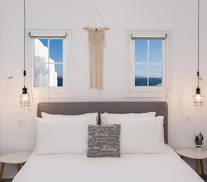 A bedroom with a bed, two windows, a macrame wall hanging, bedside lamps, and a decorative pillow.