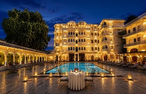 A large, illuminated building with a pool, outdoor seating, and a well-lit courtyard. - The Amar Mahal (Udaipur)