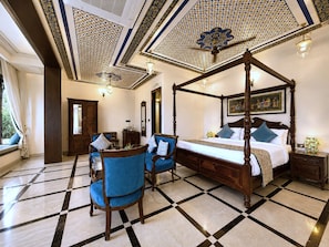 A four-poster bed, a sitting area with two chairs, a large mirror, and a window with curtains. - The Amar Mahal (Udaipur)