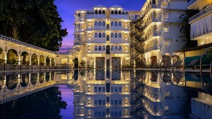 A multi-story hotel with a reflection pool, ornate balconies, and a traditional architectural style. - Amar Mahal Luxury Boutique Hotel Near Fateh Sagar Lake, Udaipur (Udaipur)
