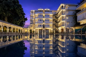 A multi-story hotel with a reflection pool, ornate balconies, and a traditional architectural style. - Amar Mahal Luxury Boutique Hotel Near Fateh Sagar Lake, Udaipur (Udaipur)