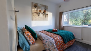 Un dormitorio con una cama, una ventana y un cuadro en la pared.