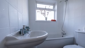 Un baño con lavamanos, bañera y retrete blancos.