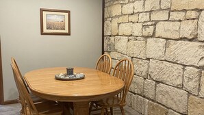 A wooden dining table with six chairs, a framed picture on the wall, and a stone wall. - Unique Space in Historic Building (Osborne)