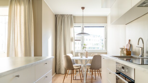 Ett modernt kök med matplats, med ett stort fönster, en hänglampa och en diskho.