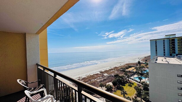 Uma varanda com vista para a praia e área da piscina.