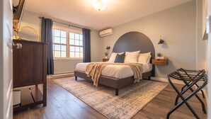 A bedroom with a bed, bedside tables, a nightstand, a dresser, a window with curtains, and a ceiling light.