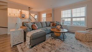 A modern living room with a gray sectional sofa, a round coffee table, and a patterned rug.