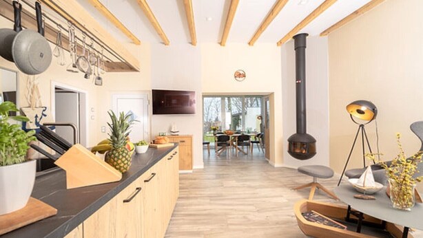 Eine moderne Küche mit Holzbalken, einer großen Kochinsel und einem Kamin.
