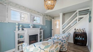 A living room with a fireplace, patterned sofas, a staircase, and a wine rack. - LakeView Getaway: Lake views & hot tub! (Lexington)