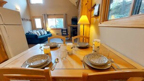 A dining area with a wooden table set for four, surrounded by chairs.