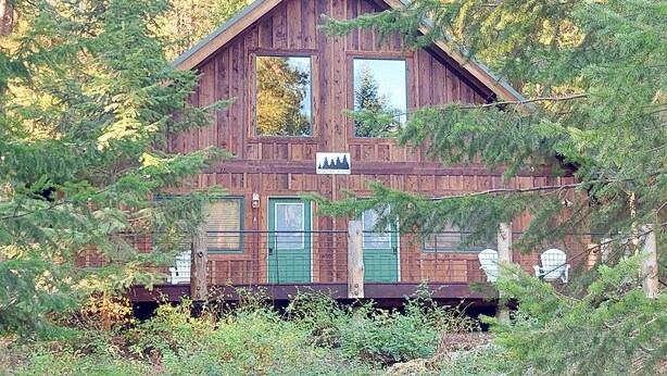 A wooden cabin with two windows, a green door, and a sign indicating it is part of the Alpine Lodge.