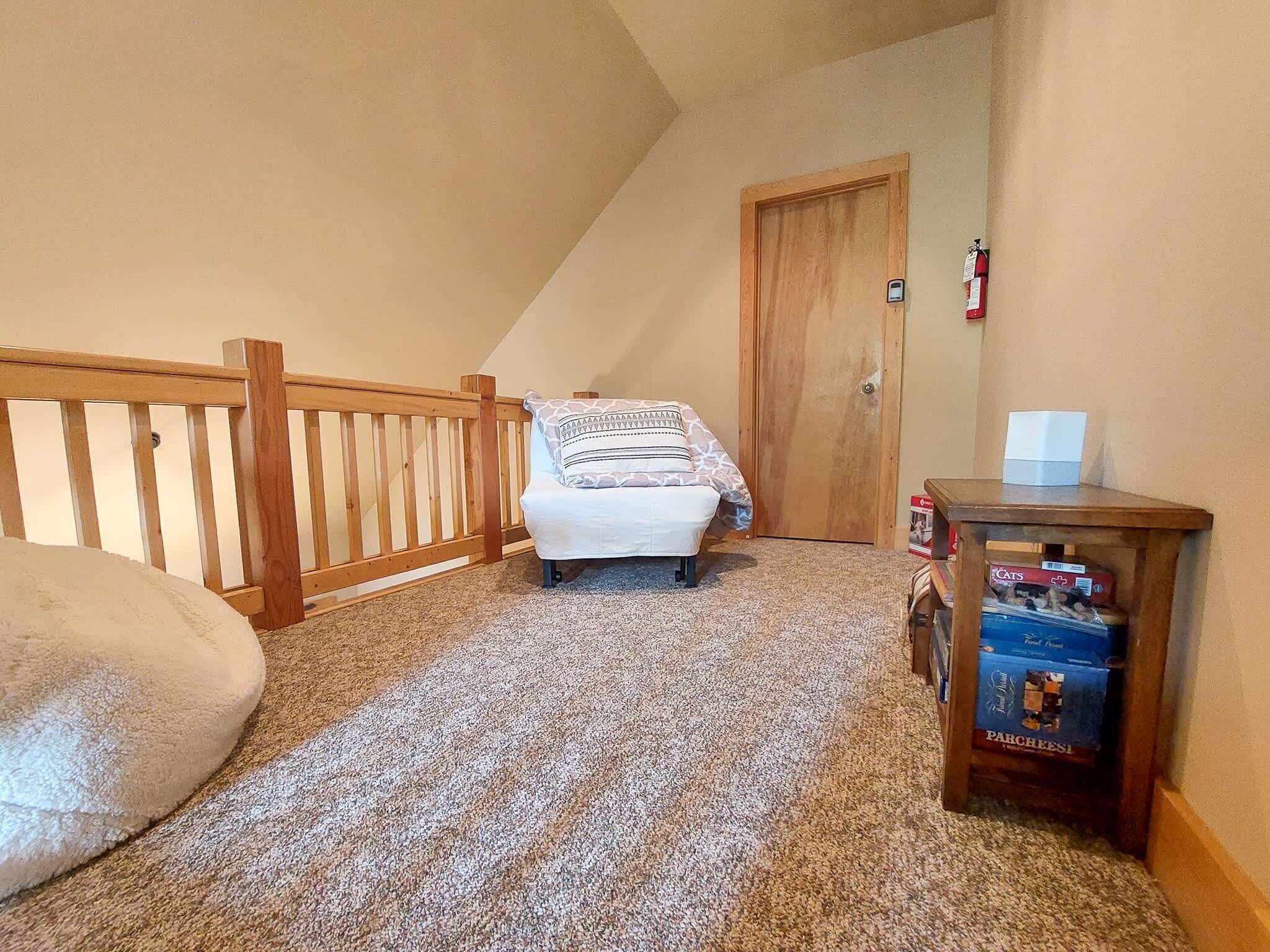 A bedroom with a bed, a wooden railing, a door, and a small table with boxes.