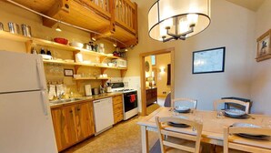 A kitchen with wooden cabinets, a refrigerator, a stove, and a dining table with chairs. - Alpine View Cabin - duplex unit B w/ queen bedroom (Winthrop)