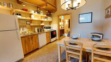 Una cocina con armarios de madera, un refrigerador, una estufa y una mesa de comedor con sillas.