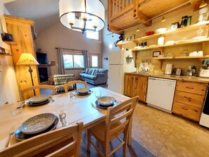 Eine gemütliche Küche mit Holzausbau, einem Esstisch für vier Personen und einem Wohnbereich mit Sofa und Fernseher.