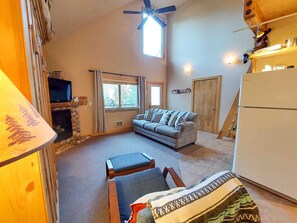 Una sala de estar acogedora con chimenea, un sofá, un televisor y un refrigerador.