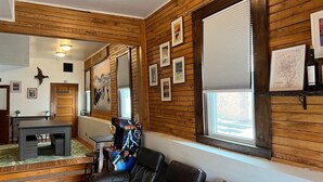 Una habitación con paneles de madera, un sofá de cuero, una mesa de comedor y cuadros enmarcados.