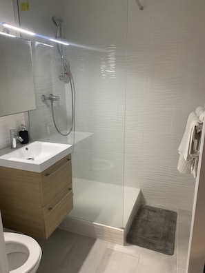 Een douche, handdoeken, zeep, toiletpapier