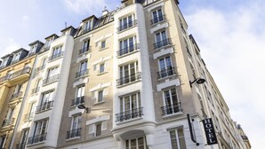 A multi-story hotel with balconies, large windows, and a sign indicating it is a hotel. - Le Daum (Paris)