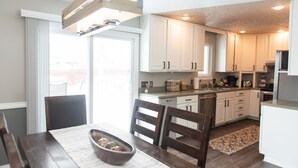 Una cocina moderna con armarios blancos, una mesa de comedor con sillas y una isla de cocina.