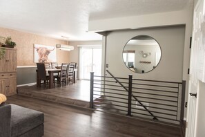 A modern interior with a dining area, staircase, and a large mirror. - Tranquil 5 bedroom home with large deck and yard (Billings)