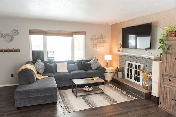 A modern living room with a sectional sofa, a fireplace, and a flat-screen TV.