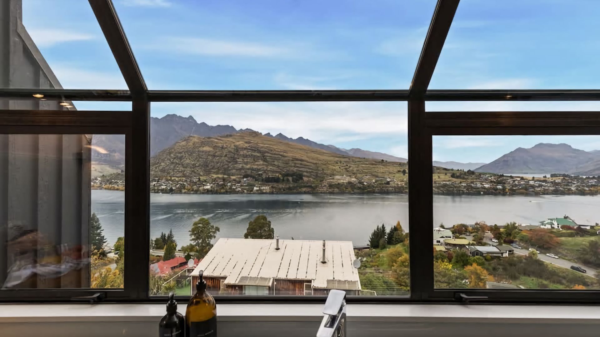 A room with large windows offering a view of a lake and mountains.
