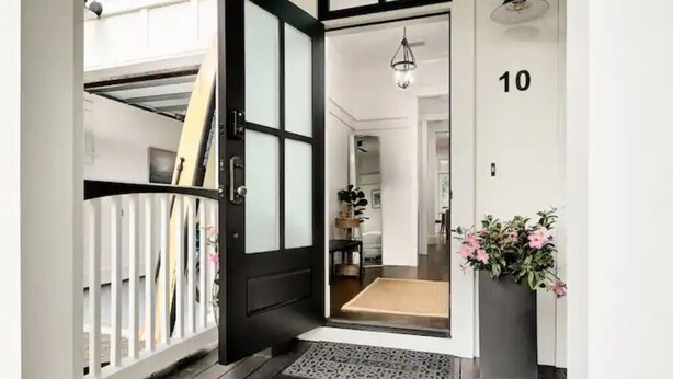 A modern entrance with a black door, a white railing, and a potted plant. - Kid friendly home with golf cart, sports gear for beach pool lake  (Inlet Beach)