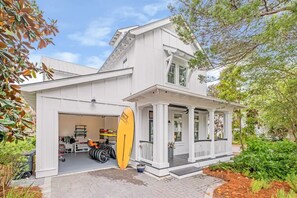 Une maison blanche à deux étages, avec un garage et une véranda couverte.
