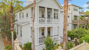 A two-story white house with a balcony on the second floor, surrounded by palm trees and a well-maintained garden. - Kid friendly home with golf cart, sports gear for beach pool lake  (Inlet Beach)
