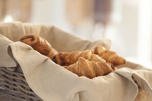 A basket of croissants on a beige cloth.