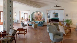 A spacious living area with a pool table, comfortable seating, and a mural on the wall. - Hotel Punta Sur (Tarifa)