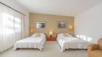 Habitación de hotel con dos camas, una mesita de noche con lámpara y dos cuadros en la pared.