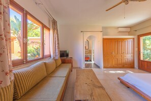 A room with a sofa, a wooden table, a TV, and a view of the outdoors. - Hotel Punta Sur (Tarifa)