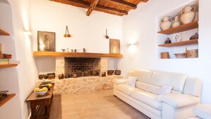 Uma sala de estar acolhedora com lareira, sofá de couro branco e prateleiras com cerâmica.