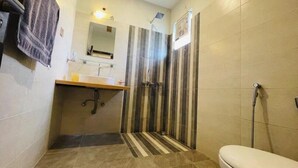 Een badkamer met douche, toilet, wastafel en spiegel.