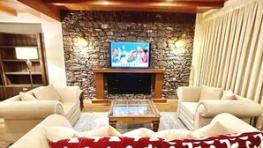 Un salon avec un mur en pierre, une cheminée et un téléviseur.